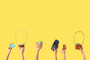 Women with Easter eggs, payment terminal and credit card on yellow background. Online shopping