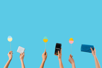 Women with Easter eggs, wallets and payment terminal on blue background. Online shopping