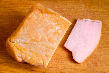 Smoked meat on a wooden cutting board. A cut slice of meat. Top view.