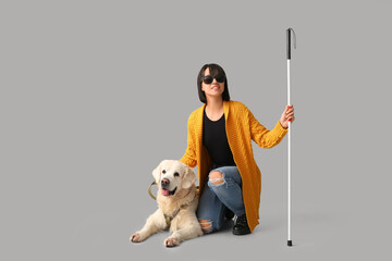 Blind woman with guide dog on grey background