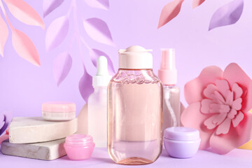 Fototapeta na wymiar Skin care cosmetics and paper flowers on lilac background