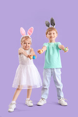 Little children in bunny ears with Easter eggs on lilac background