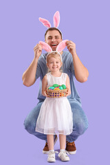 Happy family in bunny ears with Easter eggs on lilac background