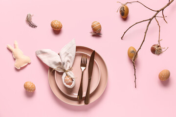 Beautiful table setting with Easter eggs, toy bunny and tree branches on pink background