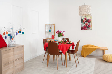 Modern interior of festive decorated dining room with Easter dining table, chest of drawers and chairs