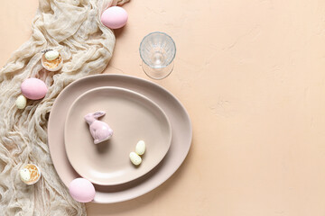Table setting for Easter celebration with painted eggs and cloth on beige background