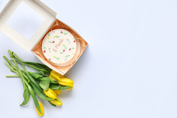 Box with sweet bento cake and beautiful yellow tulips on white background. International Women's Day