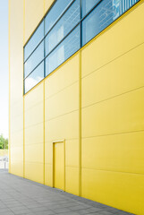 Yellow wall of modern building with window. Door in the yellow wall.
