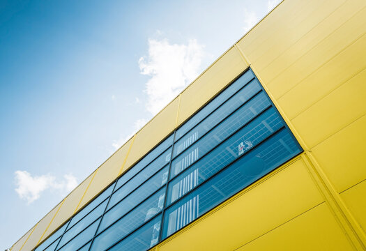 Wall of yellow building with big blue window. Clear blue sky in the background.