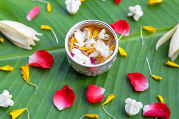 Water with jasmine flower, marigold petals, white champaka and rose petals in silver bowl. Thai tradition, Songkran festival concept