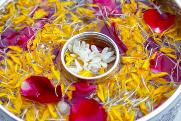 Water with jasmine flower, marigold petal and rose petals in silver bowl. Thai tradition, Songkran...