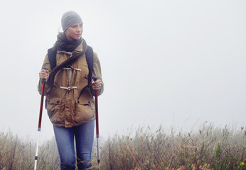 Woman, hiking and nature with trekking sticks, winter and support for fog trail in mountain. Athlete, backpack and mountaineering gear for safety in wet environment, slippery and walking for fitness