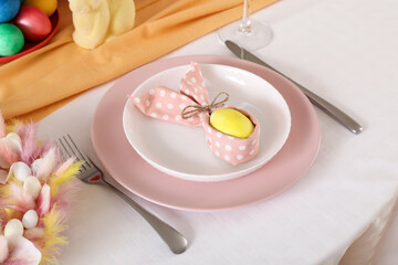 Festive table serving with painted egg in folded napkin for Easter celebration, closeup