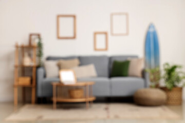 Modern comfortable living room with cozy sofa, houseplant and table, blurred view