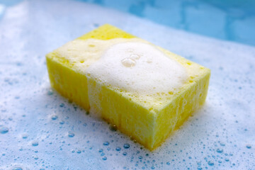Cleaning sponge in foam of dishwashing liquid. Washing dishes concept