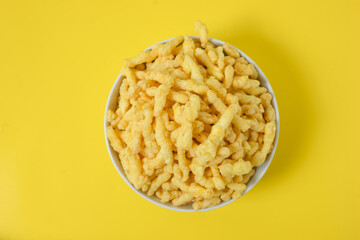 Close-up of cheese snack in bowl against yellow background. perfect for recipes, articles, catalogues, or commercials