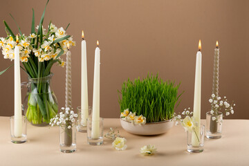 Novruz table setting with green samani wheat grass with red ribbon, daffodils, candles, kelagai and...