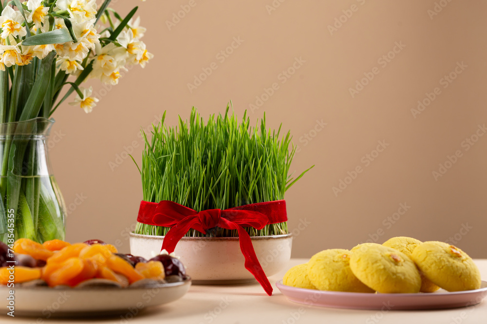 Wall mural Novruz table setting with green samani wheat grass with red ribbon, dried fruits, sweet pastry, candles, kelagai and blooming flowers, spring or new year celebration in Azerbaijan, copy space