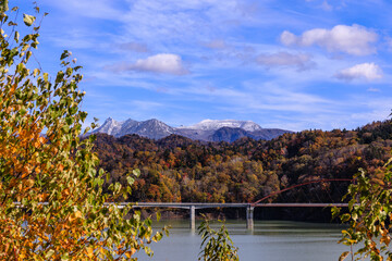 北海道夕張市、うっすら雪化粧の夕張岳とシューパロ湖の紅葉【10月】