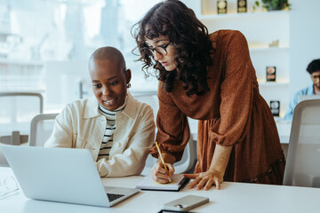 Two women collaborating on a creative project at a modern office