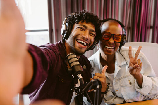 Happy podcast hosts recording a show together in a studio