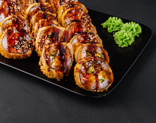 Served warm sushi with ginger and wasabi on a black stone plate