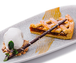 A slice of a pecan pie with ice cream and pecans