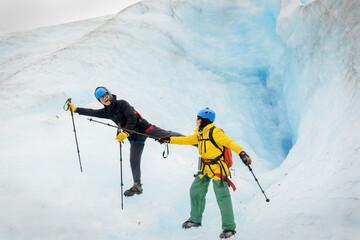 Couple holding hiking poles and doing yoga poses in front of glacier crevasse. Exit Glacier. Kenai...