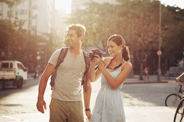 Couple, tourist and photography in street for travel, sightseeing and happiness on holiday or vacation in Brazil. Camera, man and woman with smile in city road for explore, tourism or journey in town - obrazy, fototapety, plakaty