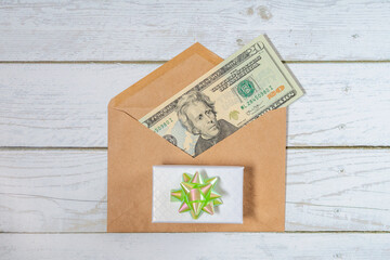 A paper envelope with 20 dollars in it on a white wooden background. Flatley with a gift	
