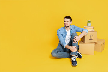 A man with boxes, on a yellow background, the concept of moving.