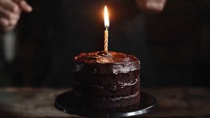 a close up of a cake candle on top of it person holding a knife in the background.