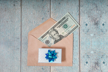 A paper envelope with 20 dollars in it on a white wooden background. Flatley with a gift	
