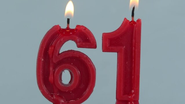 close up on timelapse melting a red number sixty one birthday candle on a white background.
