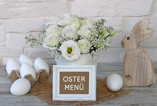 Der Text Ostermen&uuml; auf ein Schild geschrieben mit Osterdekoration und Blumen.