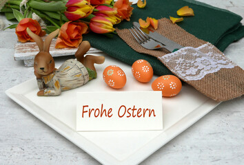 Tischdekoration zu Ostern mit Blumen,Ostereiern und einer Tischkarte mit dem Text Frohe Ostern.