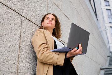 Businesswoman embraces a moment of relaxation during her break, seamlessly working on her laptop amidst the urban landscape