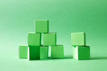 Green Cubes Organized in a Pyramid Formation on Uniform Teal Green Background Representing Eco-Friendly Development