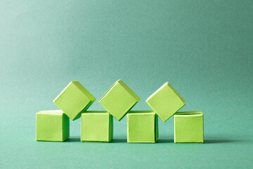 Arranged Green Cubes Casting Shadows on Green Teal Surface - Abstract Design Representing Eco-Friendly Development