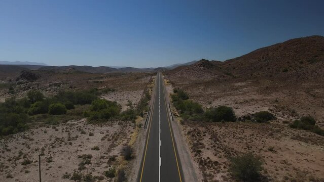 Fly with me across the Klein Karoo straight desert road with blue sky background