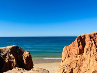 Sandstone rocky coast, blue ocean horizon, clear sky, ocean bay