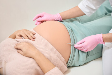 Gynecologist making Rh immunoglobulin injection into belly of pregnant woman
