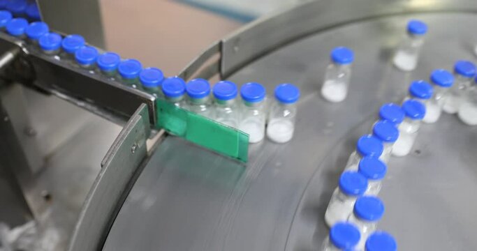 injections and vaccine flu shots drug glass vial ampoules in a medicine factory creative view of small vials collected for manufacturing small glass injection moving in a pharma equipment machinery	