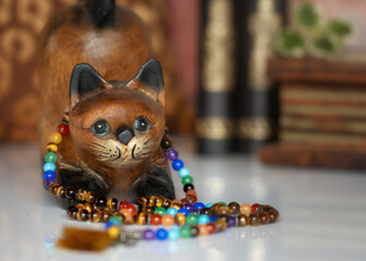 A wooden cat wearing colorful prayer beads around its neck