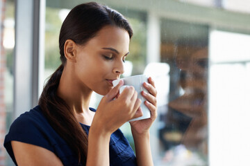 Woman, relax and drinking coffee in home for peace, calm and energy at breakfast in the morning. Matcha, tea cup and young person with espresso, latte or hot healthy beverage for wellness by window