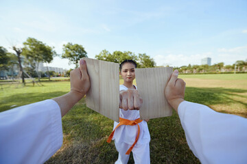 Taekwondo sportswoman breaking wooden board with her fist