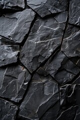 A weathered black stone wall with visible cracks. Suitable for backgrounds or texture overlays