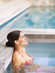 Woman, happiness and relax in jacuzzi at spa with thinking, vacation or holiday fun in summer with...