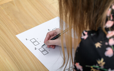 Dziewczyna wypełnia test, zaznacza długopisem odpowiedzi - obrazy, fototapety, plakaty