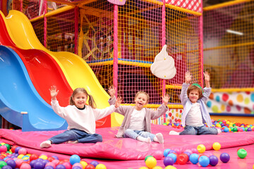 Happy kids playing in play room with slides, mats and ball pit